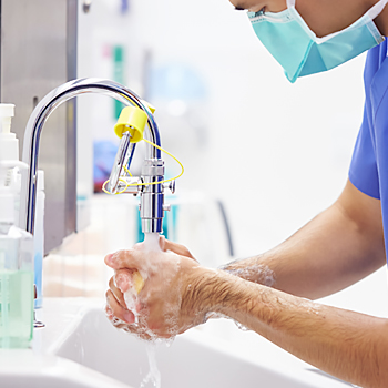 Male Surgeon Wearing Scrubs Washing Hands Before Operation In Hospital Operating Theater 