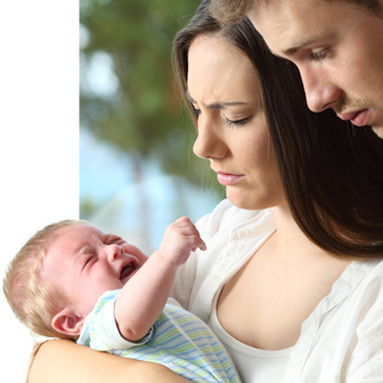 Concerned new parents looking down at their baby