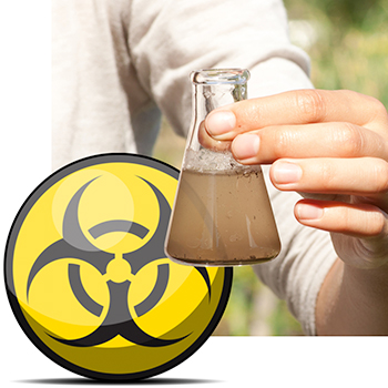 Hand holding up beaker of contaminated ground water in front of biohazard symbol