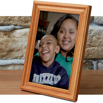 Photo of Jordan and his mother in a picture frame on a table in front of a brick wall