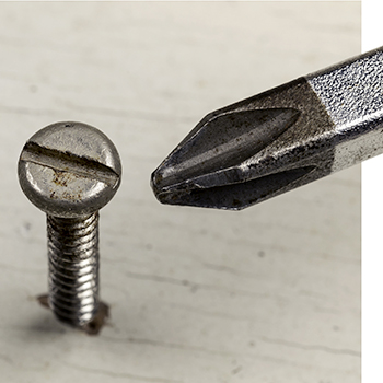 Philips head screwdriver next to standard screw