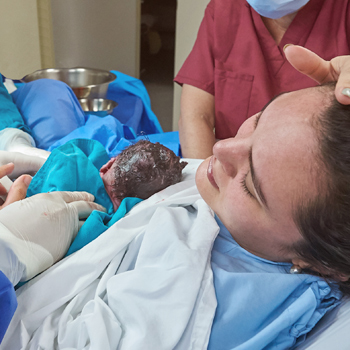 woman in hospital bed holding newborn after difficult birth